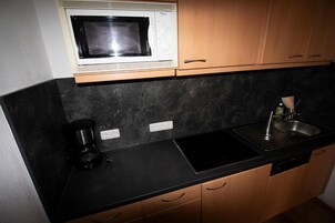 A kitchen with a microwave, coffee maker, sink, and wooden cabinets.