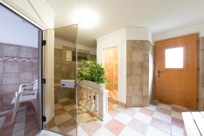 A hotel room with a glass door leading to a balcony, a wooden door, and a checkered floor.