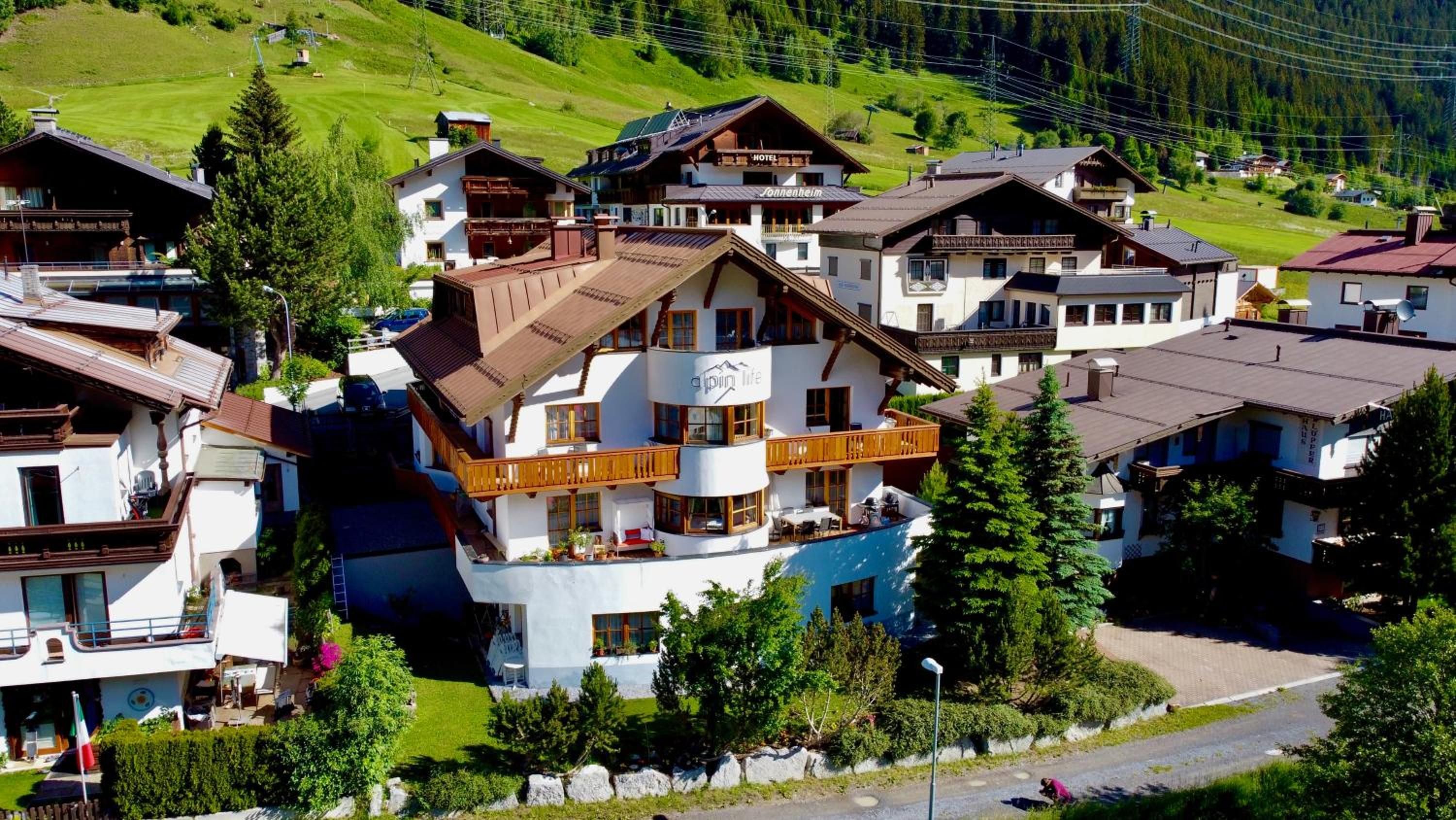 A multi-story hotel with balconies, a pool, and a ski lift in the background.