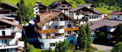 A multi-story hotel with balconies, a pool, and a ski lift in the background.