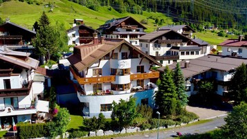 A multi-story hotel with balconies, a pool, and a ski lift in the background.