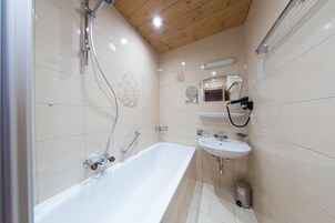 Un baño con bañera, lavabo, espejo y ducha.