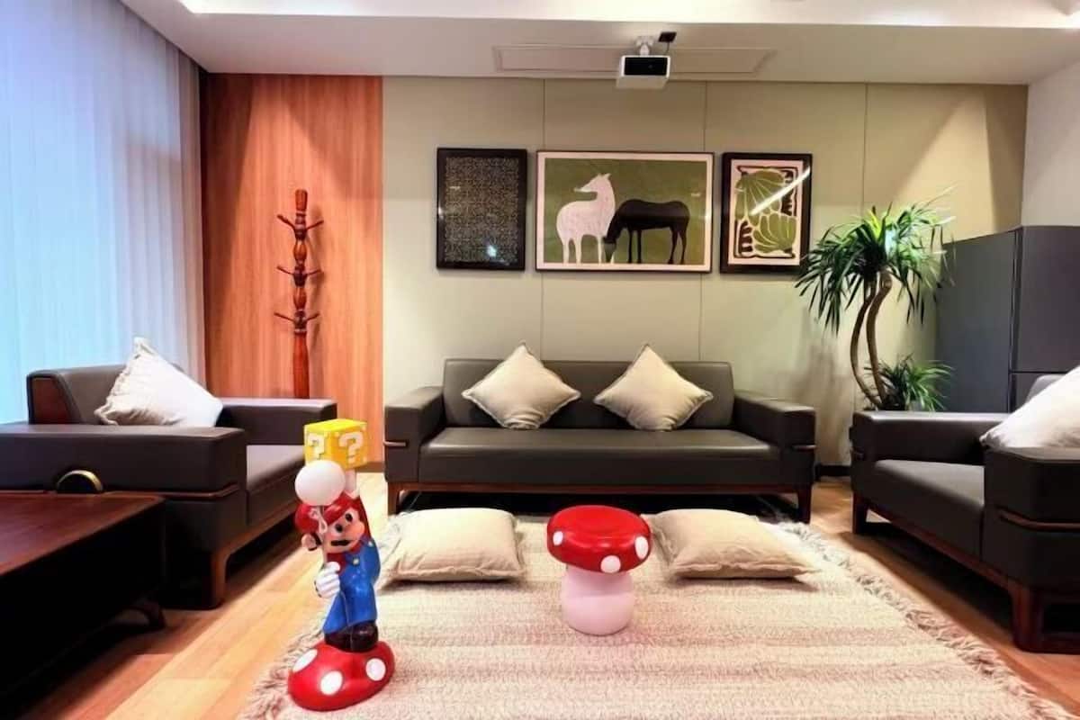 A living room with a sofa, two armchairs, a coffee table, and a Mario figurine.