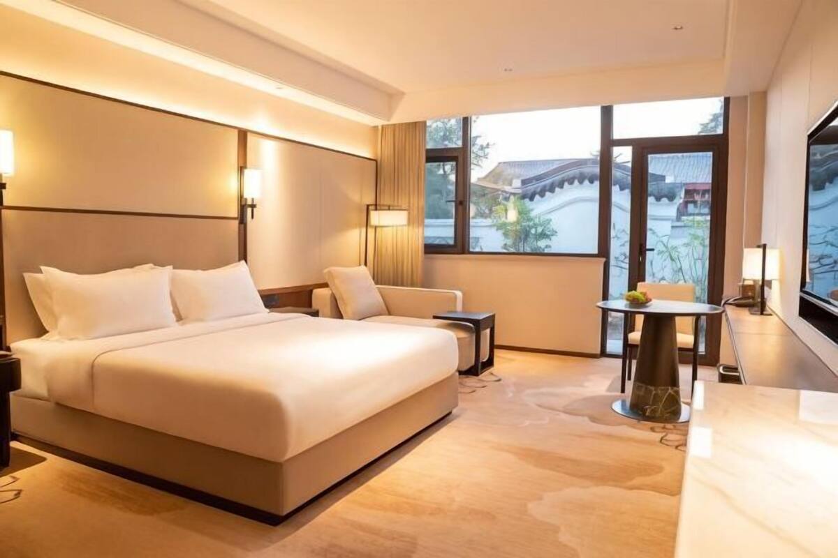 A hotel room with a large bed, a small table, a chair, and a TV.