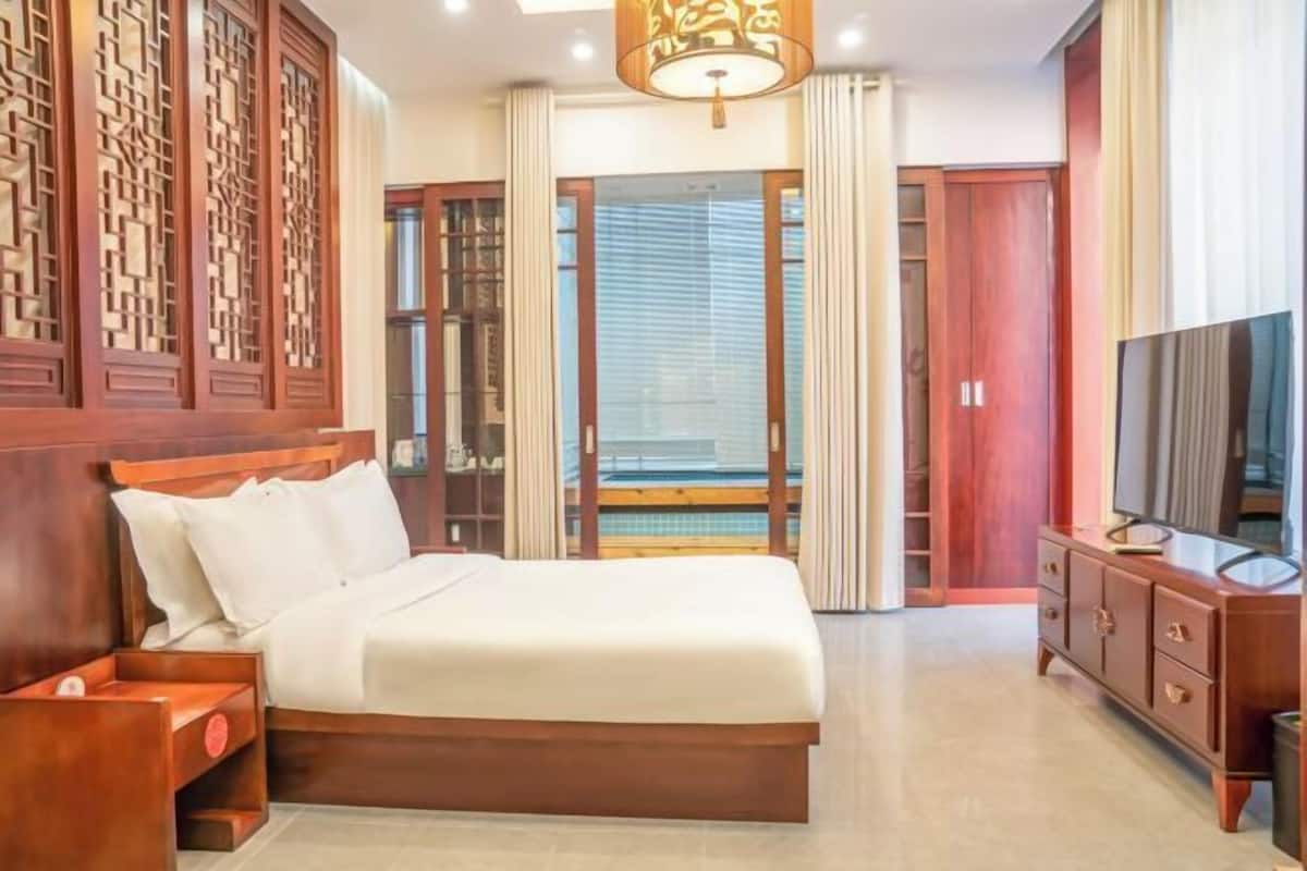 A hotel room with a wooden bed, a TV, a wardrobe, and a balcony with a view.
