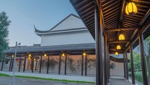 A traditional building with a tiled roof and a covered walkway with hanging lights. - Good Fortune Hot Spring Hotel (Donghai)