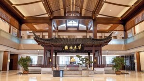 A spacious lobby with a traditional Chinese architectural style, featuring a central altar and potted plants. - Good Fortune Hot Spring Hotel (Donghai)
