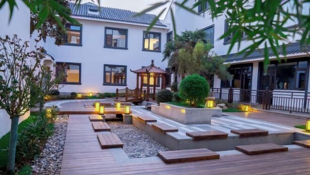 A courtyard with a wooden deck, stone steps, and a gazebo. - Good Fortune Hot Spring Hotel (Donghai)