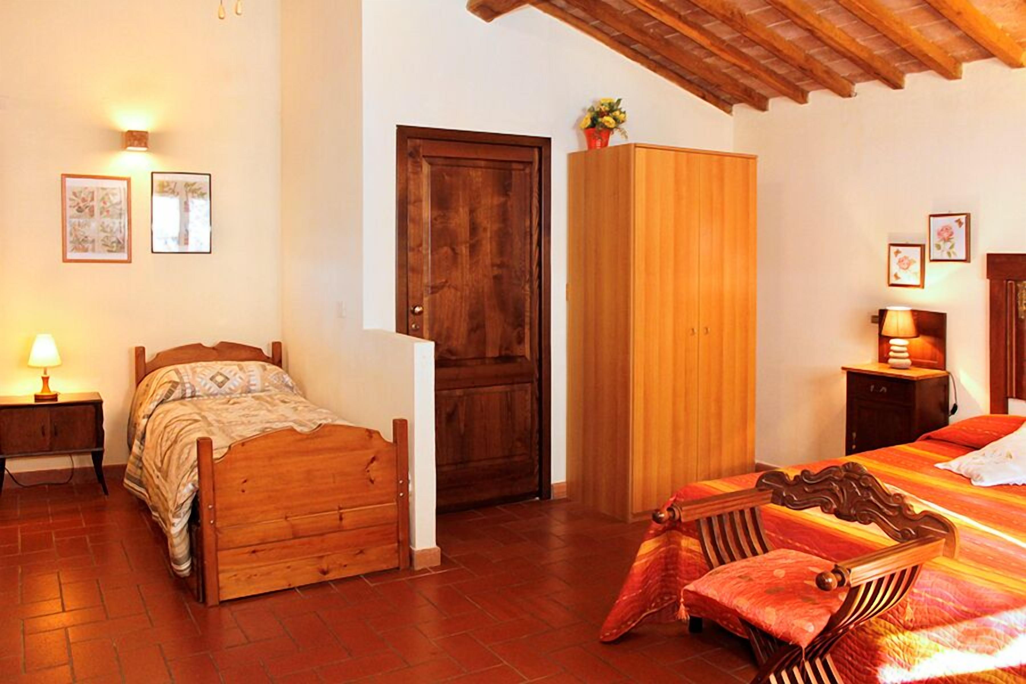 A bedroom with a wooden bed, a wardrobe, a nightstand, and a lamp.