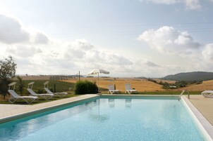 Una piscina al aire libre de temporada, sombrillas