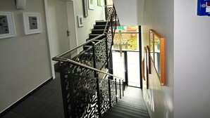 A staircase with a patterned railing, a door at the top, and framed pictures on the walls.
