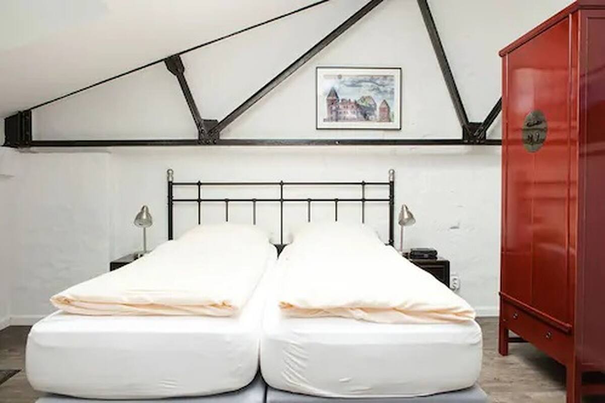 A room with a bed, a red cabinet, and a picture on the wall.