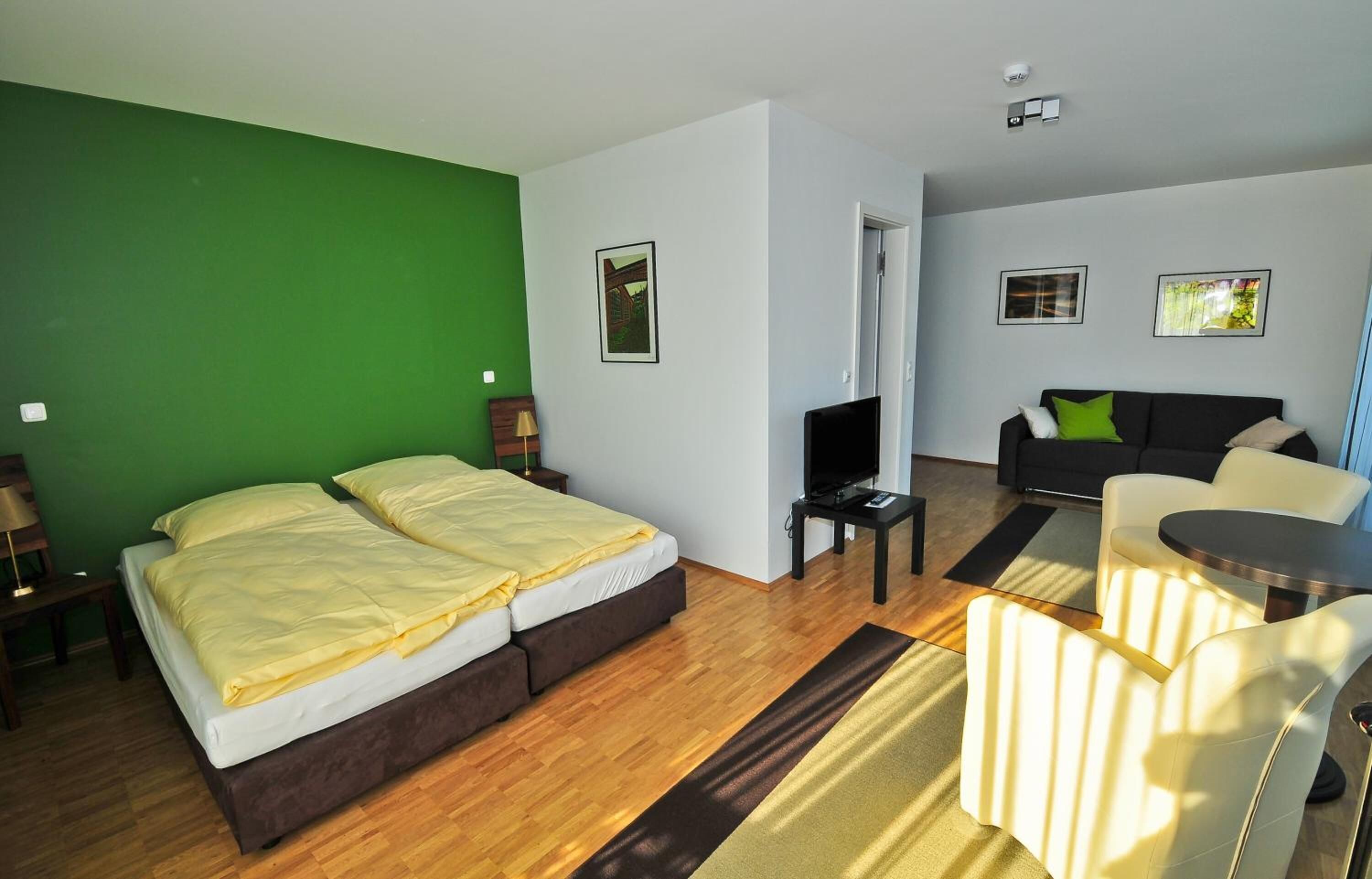 Et hotelværelse med seng, sofa, fjernsyn og et lille bord.
