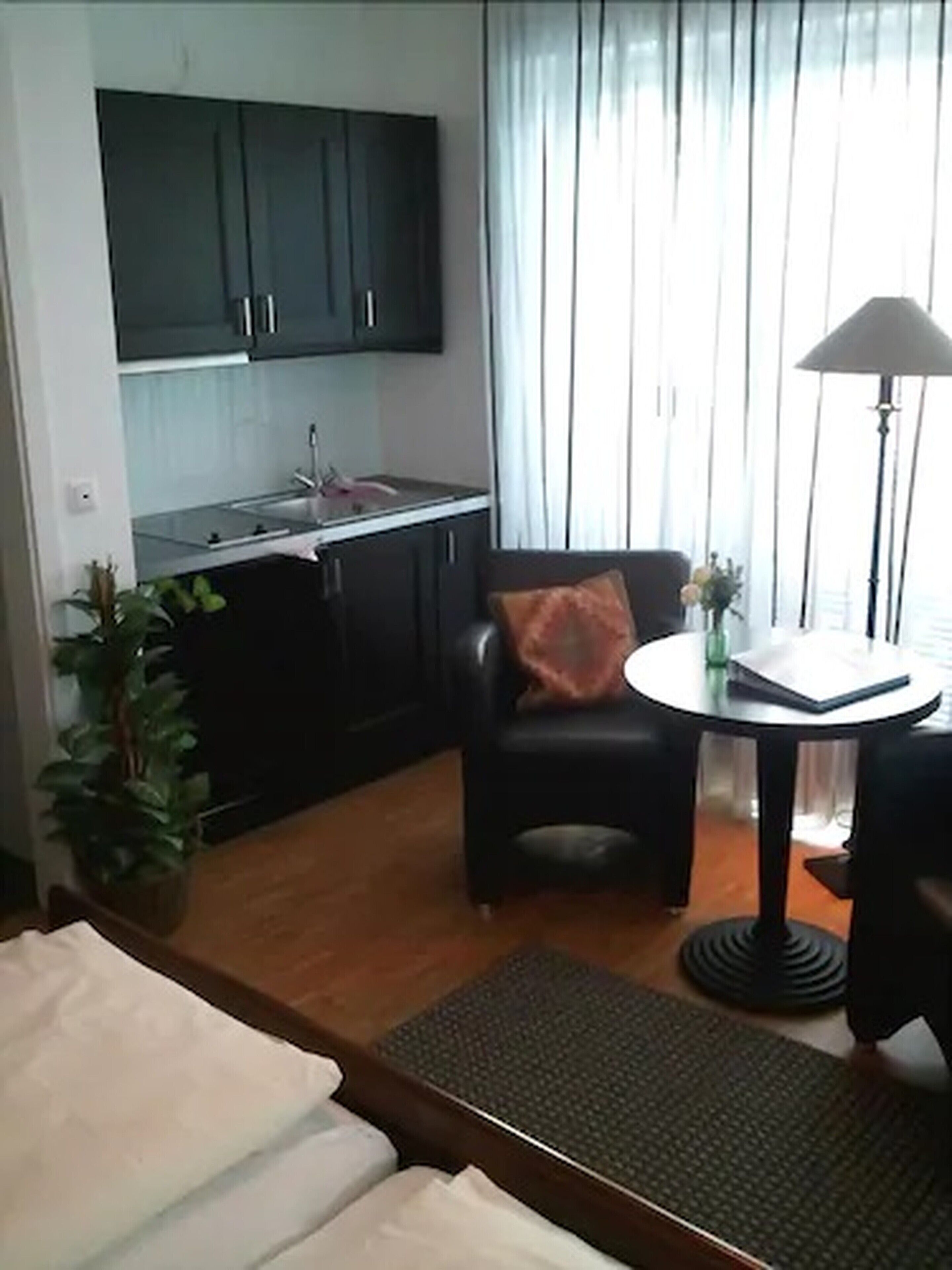 A compact living space with a kitchenette, a dining area with a table and chair, and a bed.