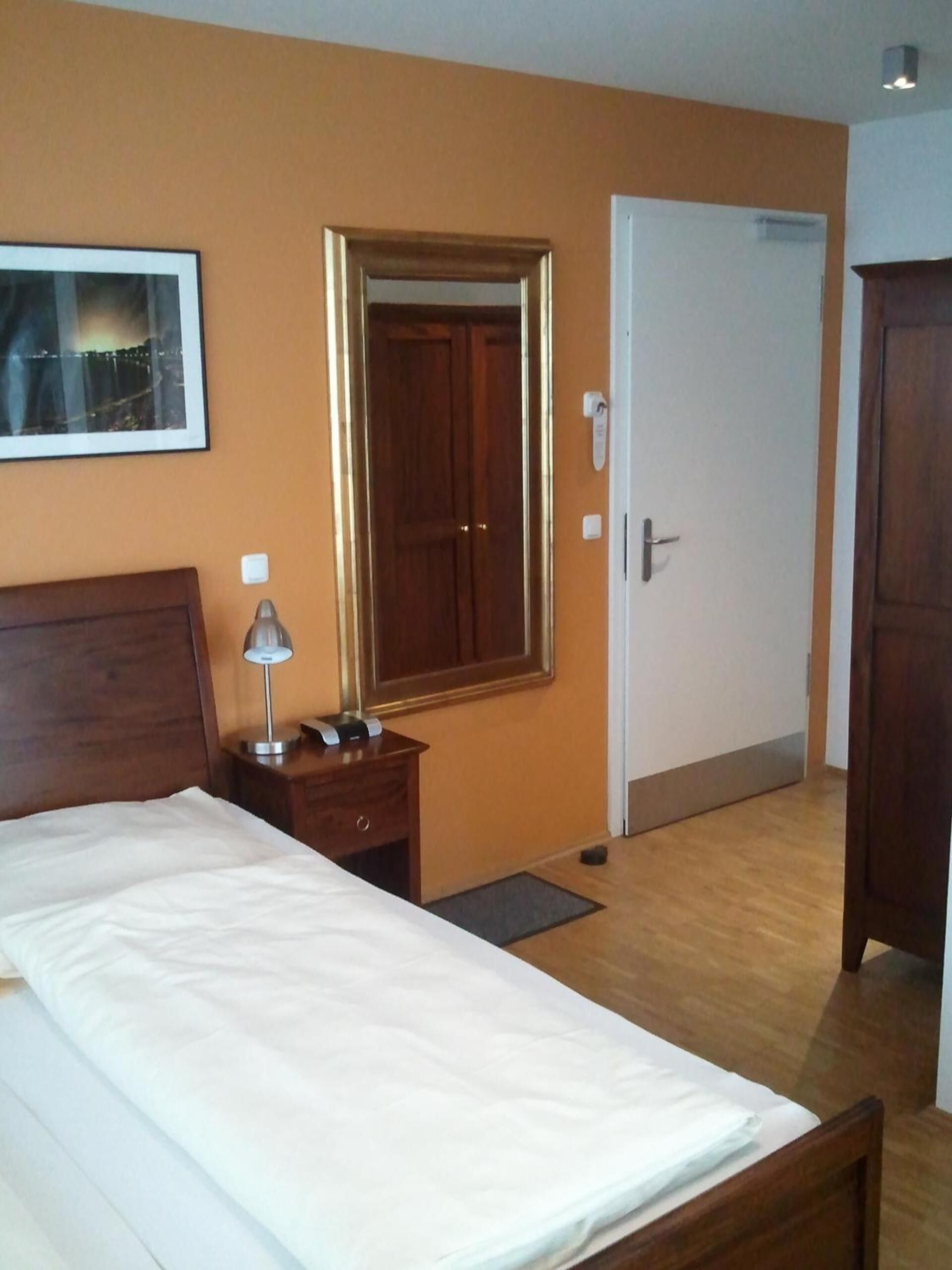 Ein Hotelzimmer mit Bett, Nachttisch, Lampe und Tür.