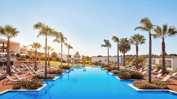 A pool area with lounge chairs and palm trees. - Tivoli Alvor Algarve - All Inclusive Resort (Portimão)
