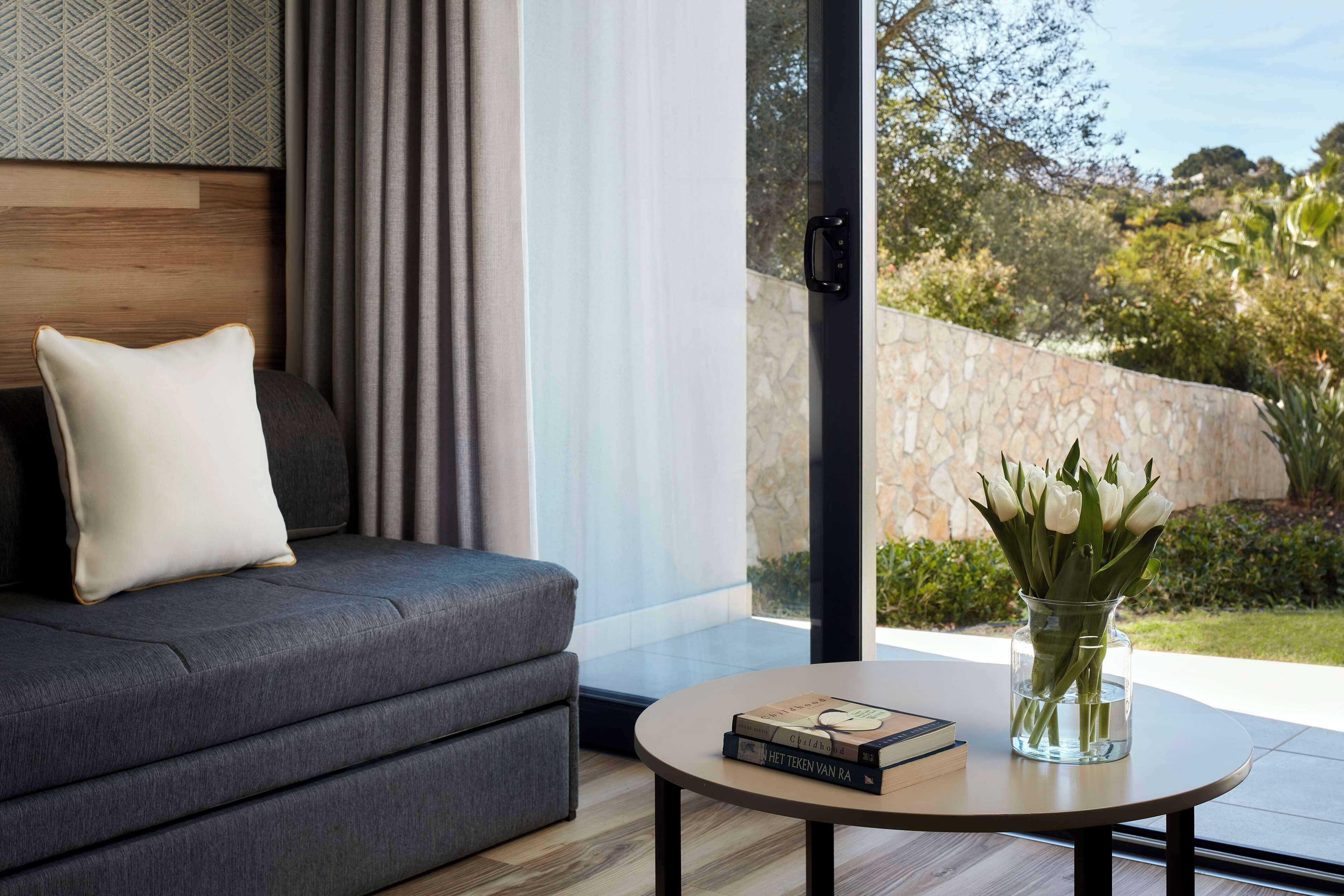 A modern living room with a grey sofa, a round coffee table, and a vase with flowers.