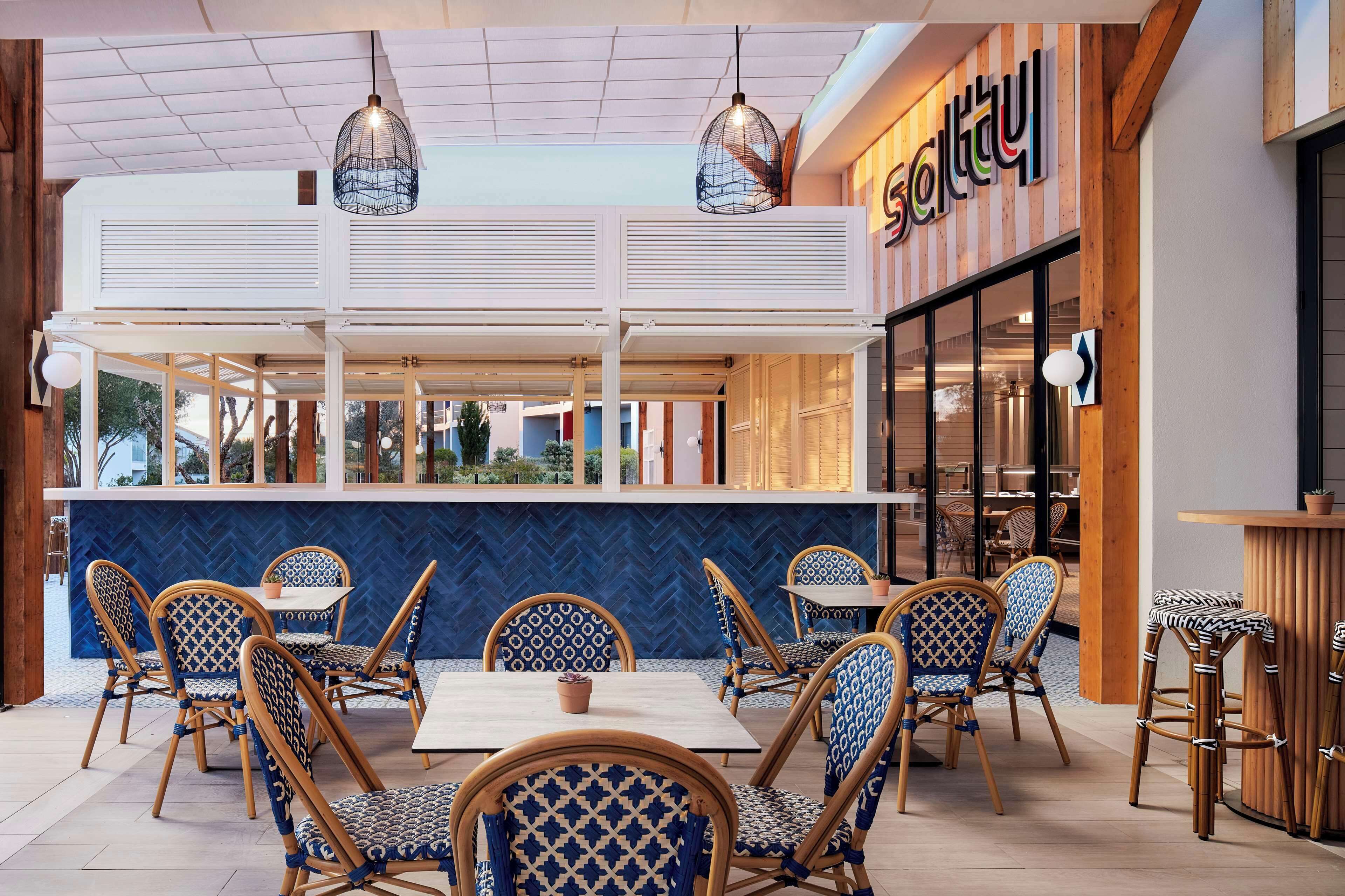 An outdoor dining area with wicker chairs and tables, a counter, and a view of the street.