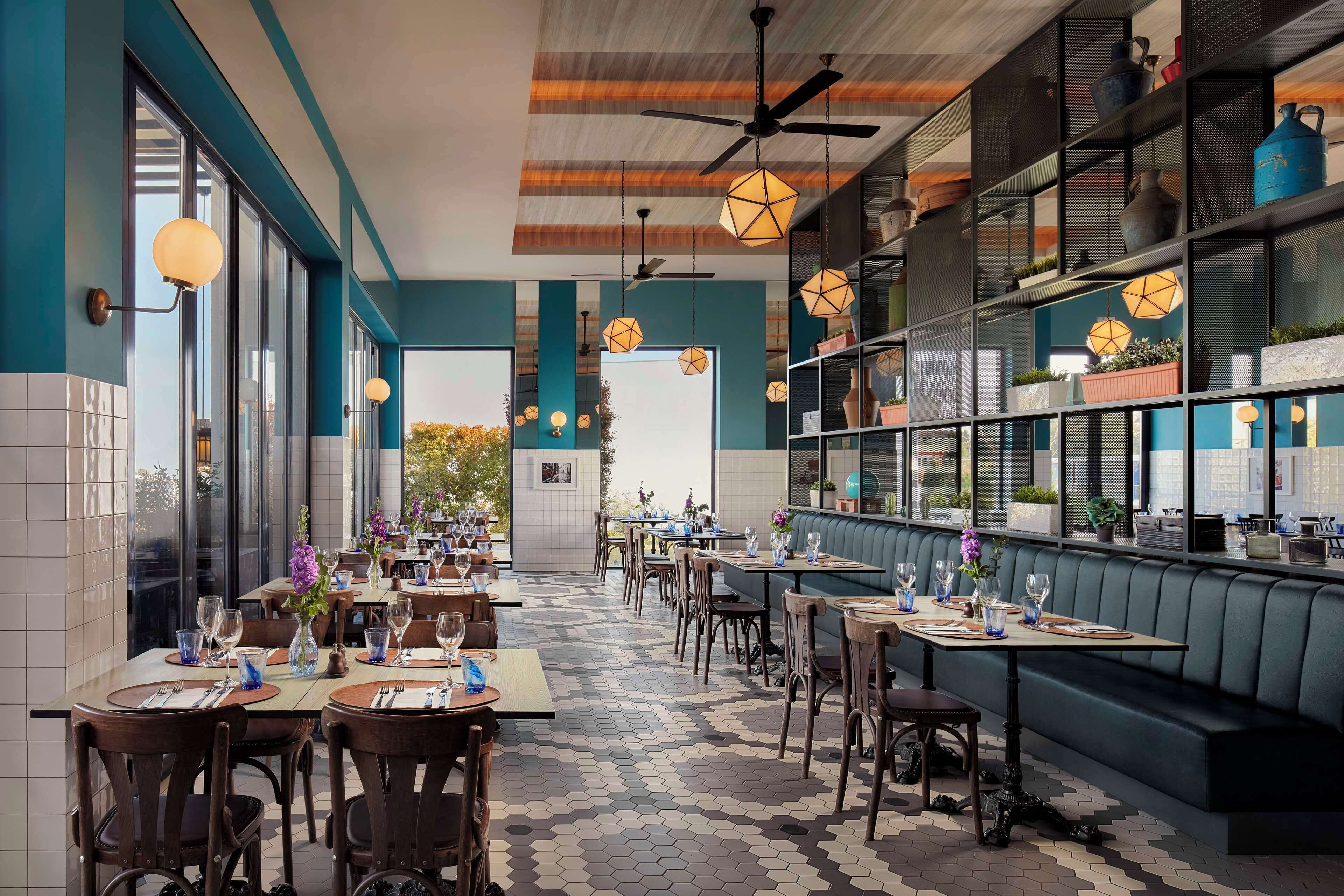 Un restaurante con mesas dispuestas para comer, una zona de bar y una sección de estar con vistas.