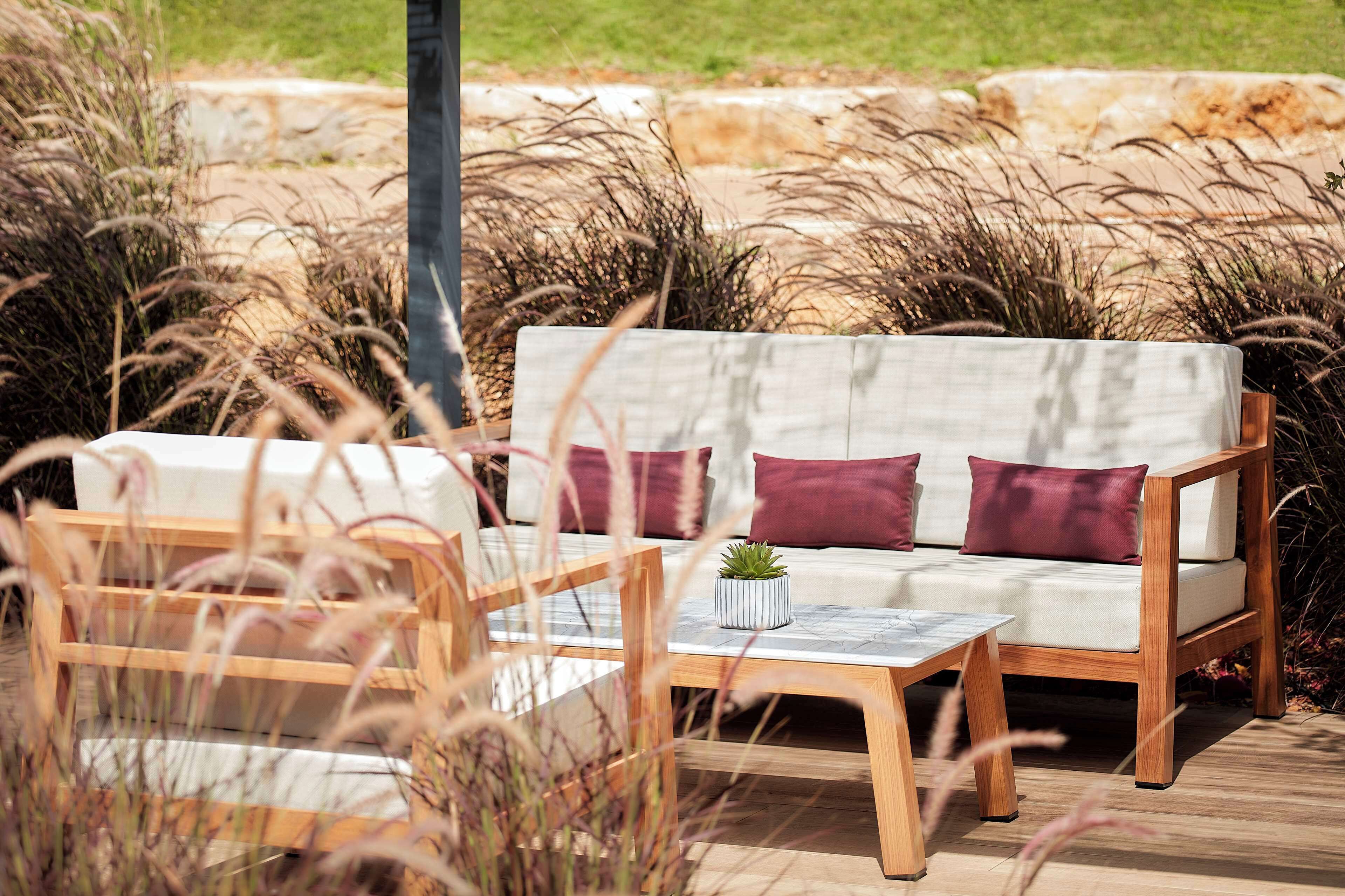 An outdoor seating area with a sofa, cushions, a small table, and a potted plant.