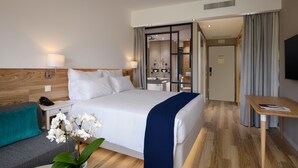 A modern hotel room with a large bed, bedside tables, a desk, and a bathroom visible through a sliding door. - Tivoli Alvor Algarve - All Inclusive Resort (Portimão)