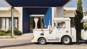 A vintage-style food truck parked in front of a building with a blue entrance and a sign that reads 'PRIVATE TRANSPORT.' - Tivoli Alvor Algarve - All Inclusive Resort (Portimão)