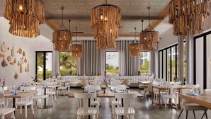 A dining area with white chairs, tables set with glassware, and hanging wooden chandeliers. - Tivoli Alvor Algarve - All Inclusive Resort (Portimão)