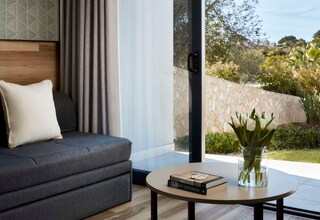 A modern living room with a grey sofa, a round coffee table, and a vase of white flowers.