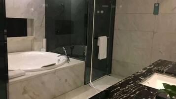 Un baño moderno con bañera, cabina de ducha de vidrio y encimera de mármol.