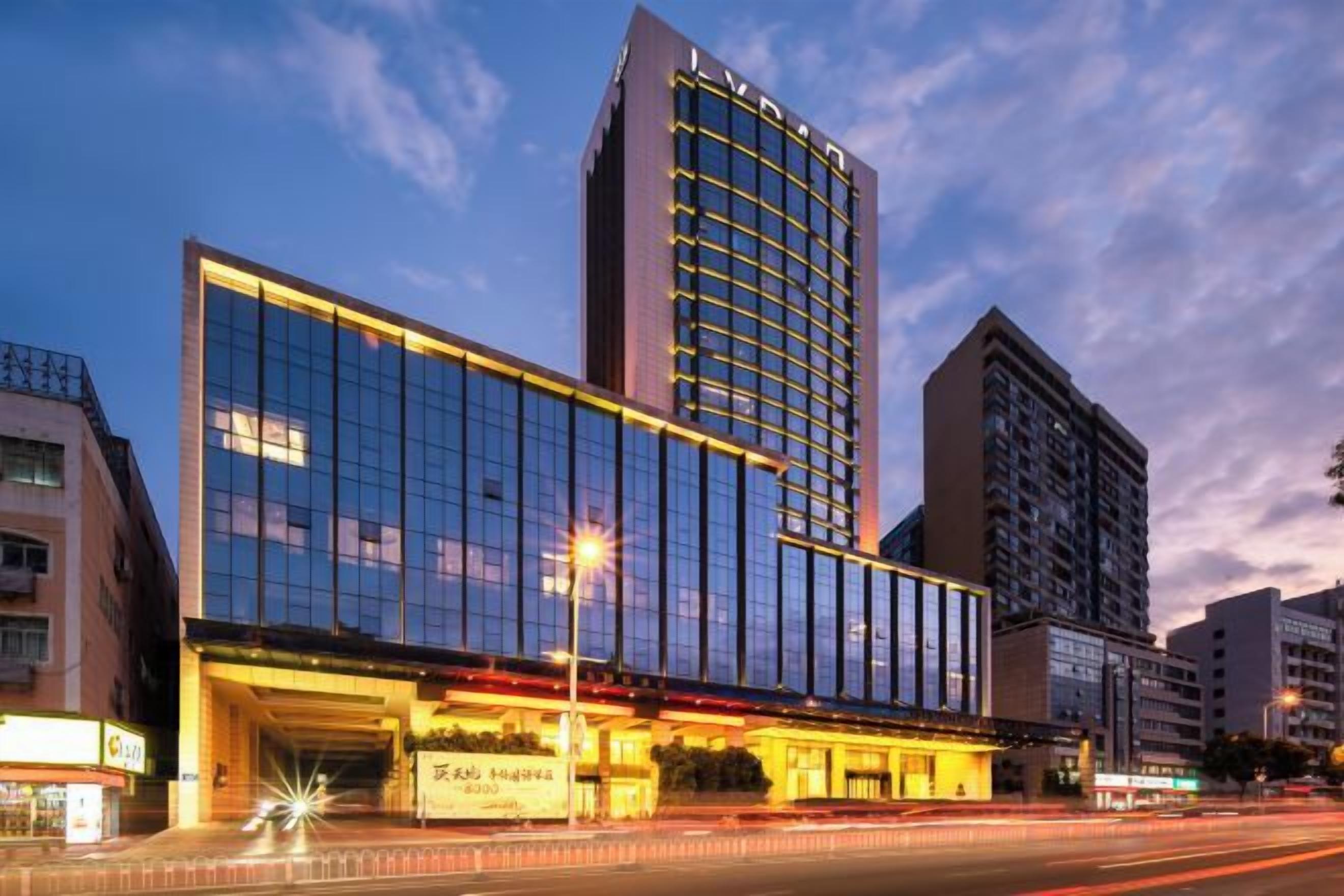 A modern hotel with a glass facade, a prominent entrance, and a parking garage.