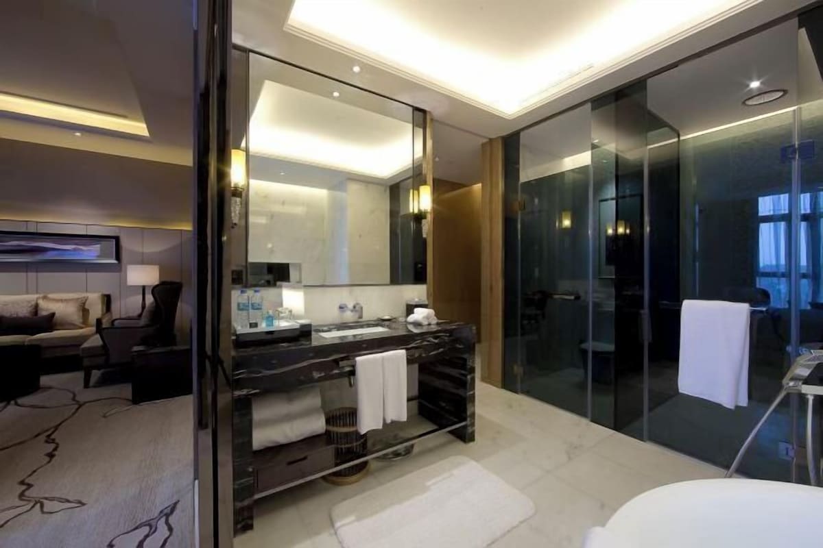 Une salle de bain moderne avec une douche à parois de verre, un meuble-lavabo en marbre et un grand miroir.