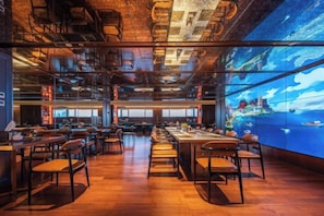 A spacious restaurant with high ceilings and exposed ductwork, featuring a large digital screen displaying a scenic view. - Lvdao International Hotel (Quanzhou)