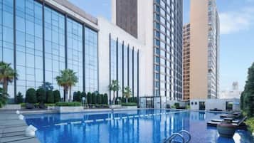 Zona de piscina con edificios modernos al fondo.