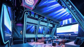 Un salón futurista con techo curvo, pantallas grandes y asientos modernos.