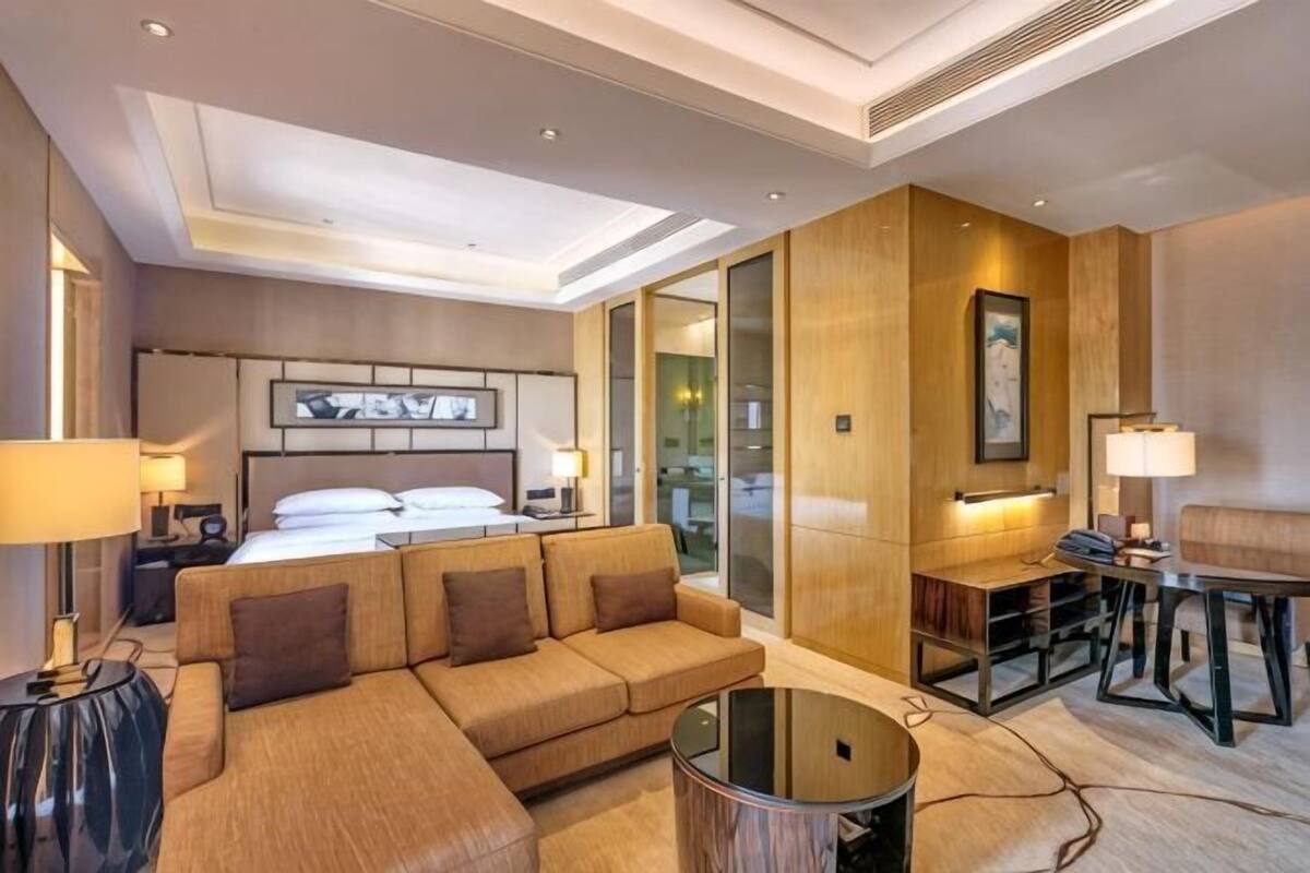 Habitación de hotel con una cama grande, un sofá, una mesa de centro y un escritorio con una lámpara.