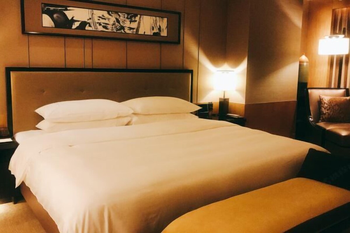 Une chambre d’hôtel avec un grand lit, une table de chevet, une lampe et une chaise.