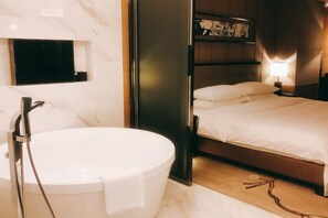 Une salle de bain moderne avec une baignoire, un miroir et un lit avec une table de chevet.