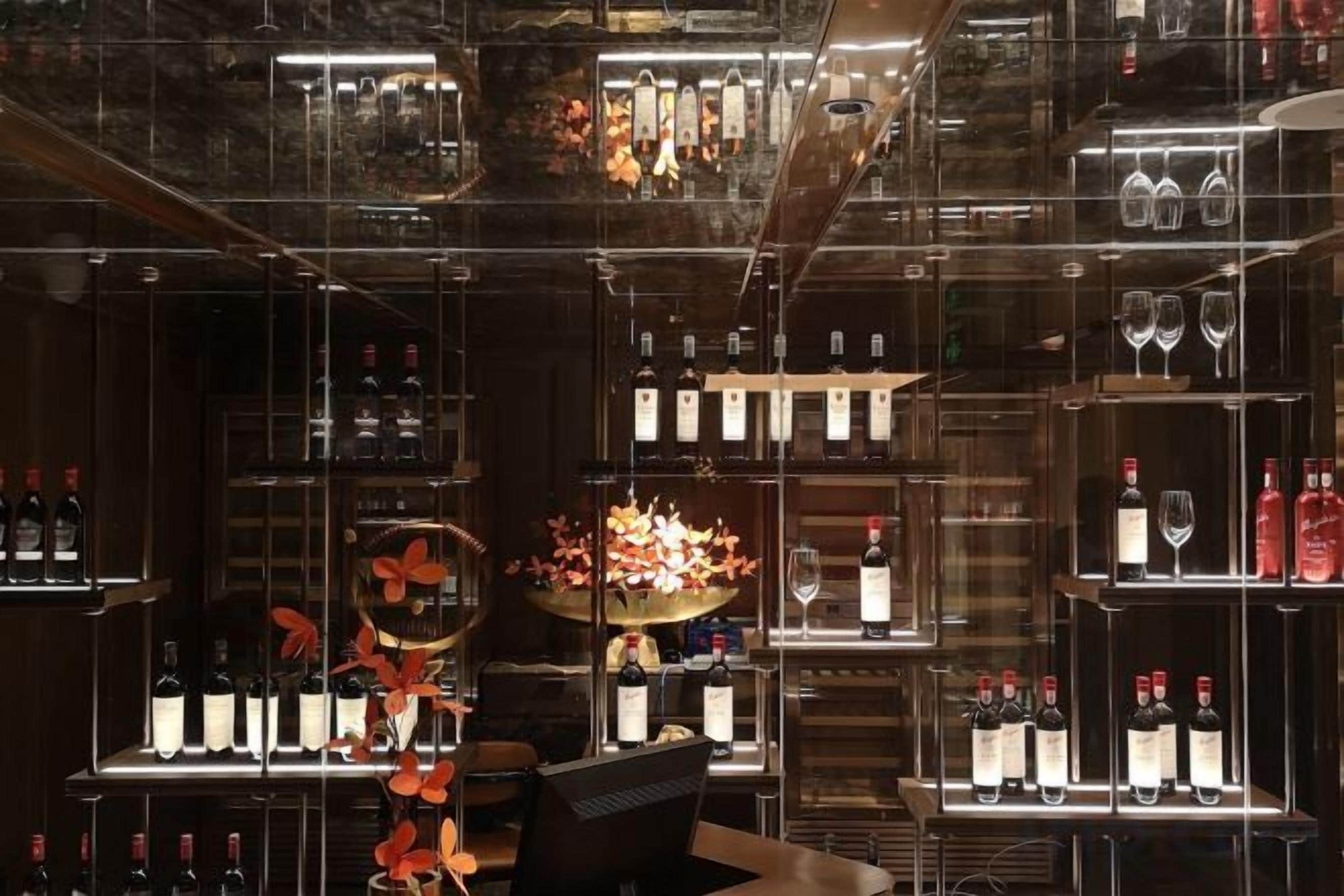A bar area with shelves of bottles and glasses, a central floral arrangement, and a seating area.