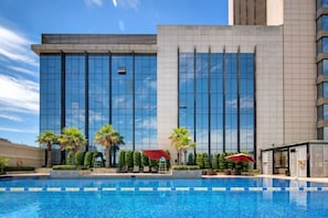 A hotel with a swimming pool, modern architecture, and palm trees. - Lvdao International Hotel (Quanzhou)