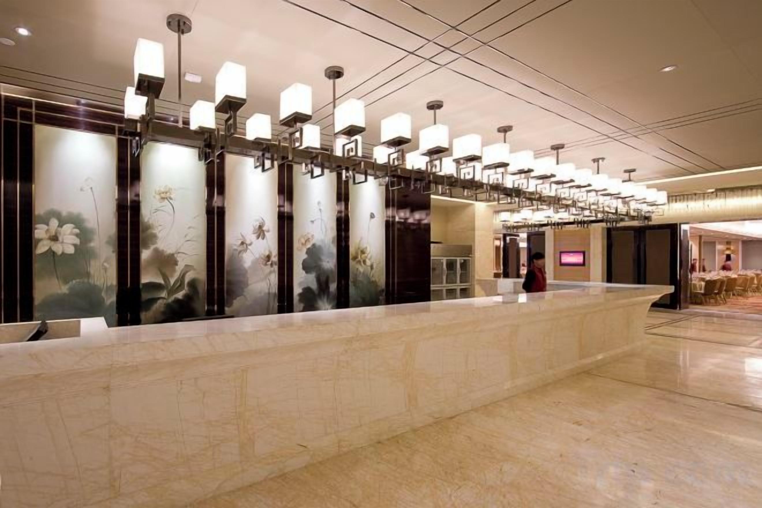 A reception area with a marble counter, wall-mounted lamps, and a decorative mural.