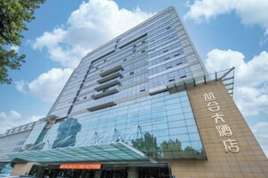 A modern hotel with a reflective glass facade and a prominent entrance.