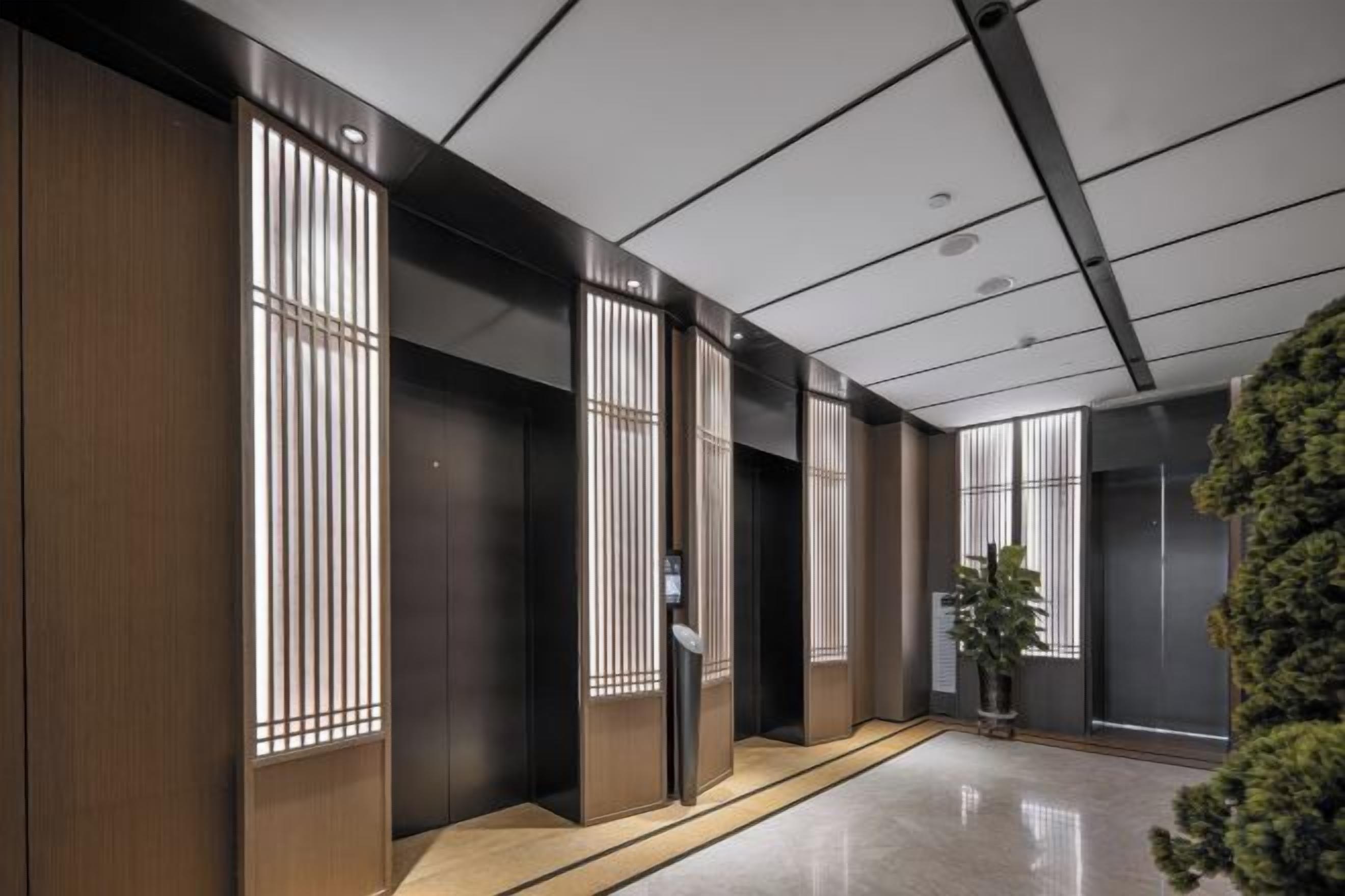 A hallway with wooden paneling and vertical blinds, a potted plant, and a modern ceiling design.