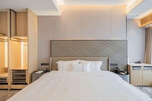 Una habitación de hotel moderna con una cama grande, un escritorio y un armario.