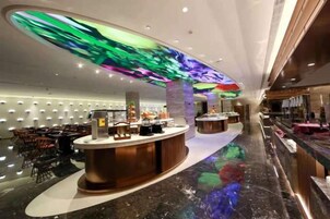 Un vestíbulo de hotel con mostrador de recepción, zona de estar y techo decorativo.