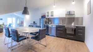 A modern kitchen with stainless steel appliances, a dining area with a table and chairs, and a bright, open layout. - Geldingsá Apartment (Akureyri)