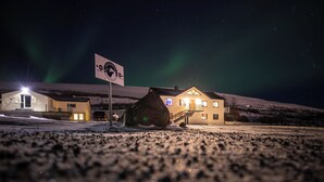 A building with a sign indicating it is an apartment complex, a staircase leading to the entrance, and a snowy landscape in the background. - Geldingsá Apartment (Akureyri)