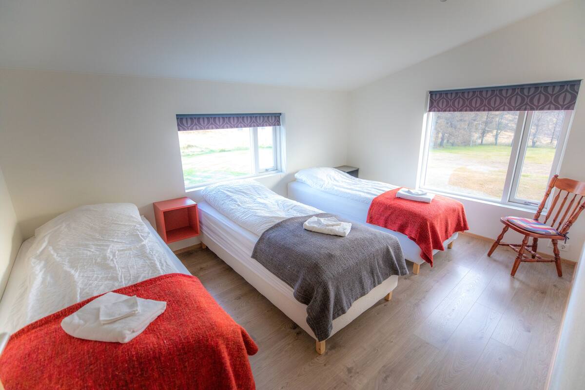 A room with two beds, a chair, and a window.