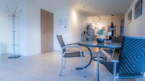 A modern dining area with a round table, two chairs, and a floor lamp. - Geldingsá Apartment (Akureyri)