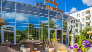 A hotel with a glass facade, outdoor seating, and a sign reading "NEW WINCHESTER". - New Living Home Residenzhotel Hamburg (Hamburg)