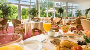 A dining area with tables set for breakfast, featuring a variety of food and drinks. - New Living Home Residenzhotel Hamburg (Hamburg)